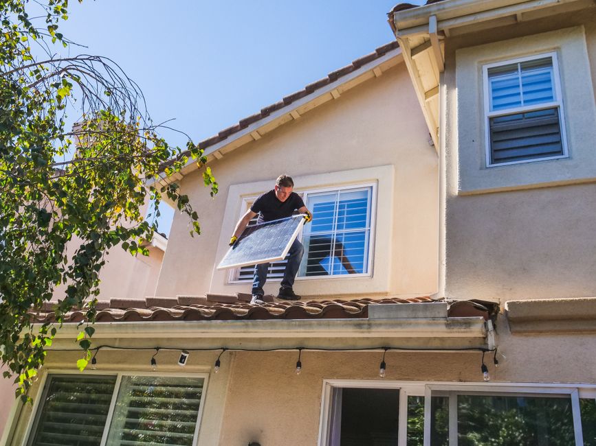 technician cleaning clogged roof rain gutters on a suburban residential house — gutter cleaning in Chattanooga, TN